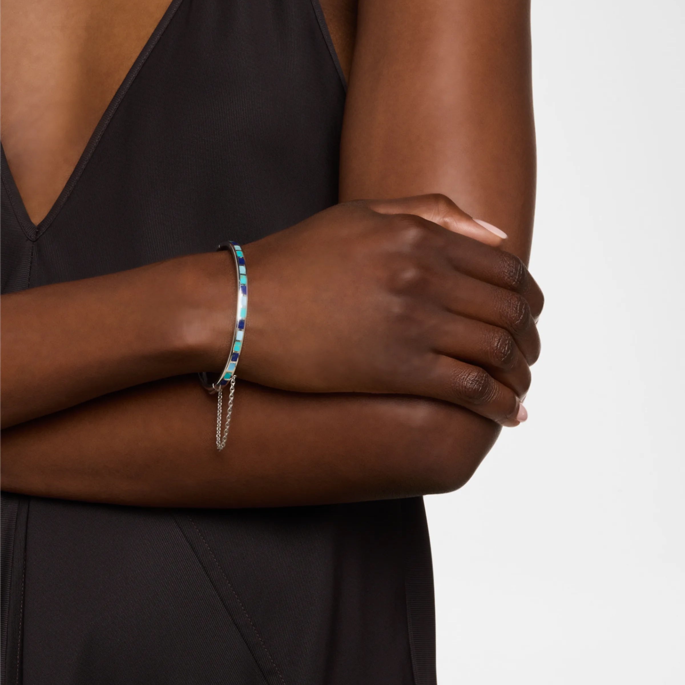 Model wearing sterling silver multi-blue enamel mosaic bangle bracelet with safety chain on wrist by Jan Leslie.