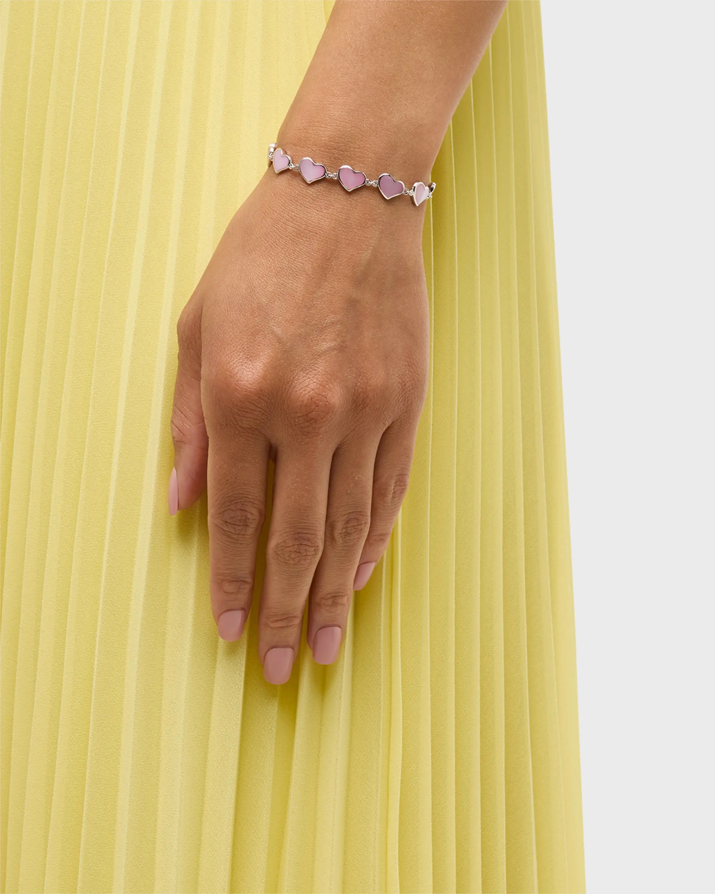 Model in yellow pleated skirt wearing pink mother-of-pearl heart link sterling silver bracelet — Jan Leslie