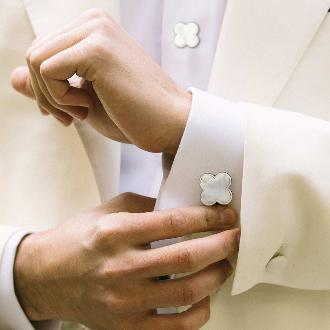 Close up of a male models wrist and torso wearing Jan Leslie's Mother of Pearl Four Leaf Clover Sterling Silver Cufflinks and Tuxedo Studs on a white tuxedo shirt with off white tuxedo jacket.