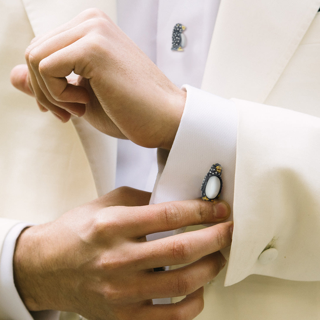 Close up of male model's wrist and torso wearing Jan Leslie's Gemstone Penguin Sterling Silver Cufflinks and Tuxedo Studs on a white cuffed tuxedo shirt and off white tuxedo jacket.