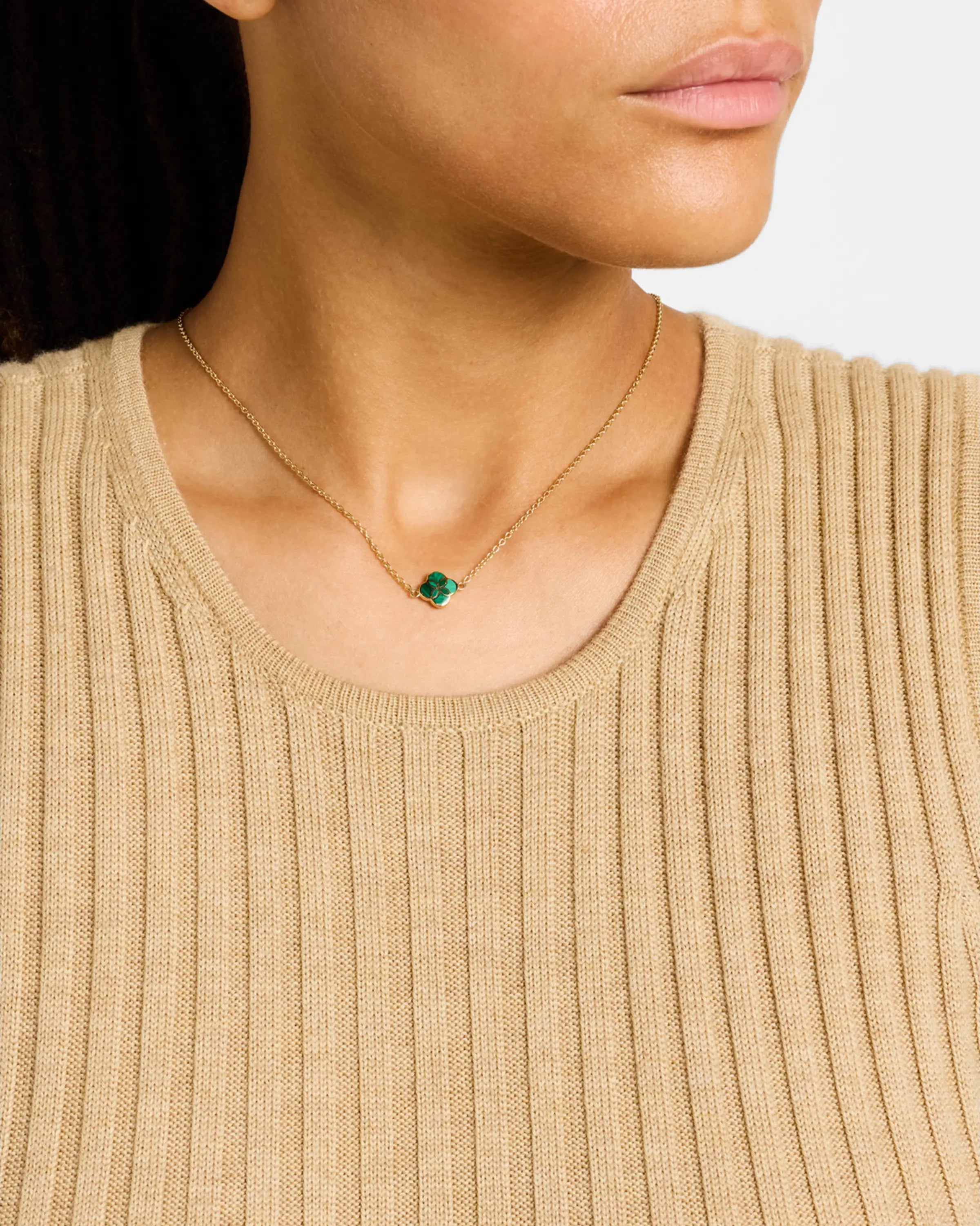 Model in beige ribbed sweater wearing malachite quatrefoil gold pendant necklace, profile view — Jan Leslie