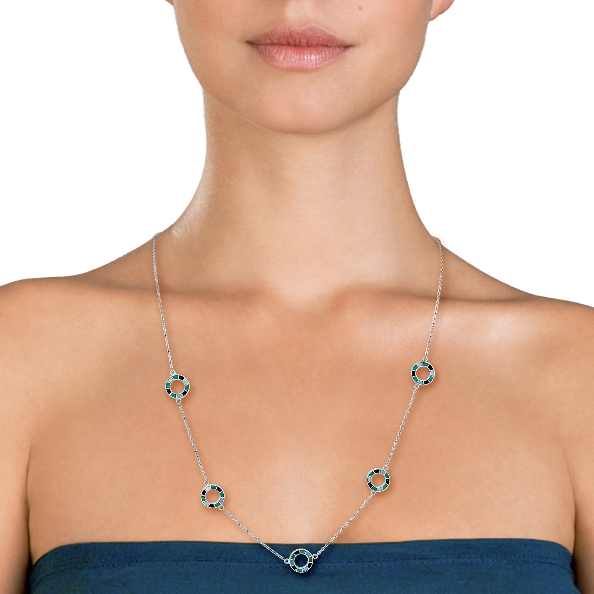 Woman in teal strapless dress wearing a long sterling silver station necklace with five open circle pendants in green and black enamel mosaic detail.