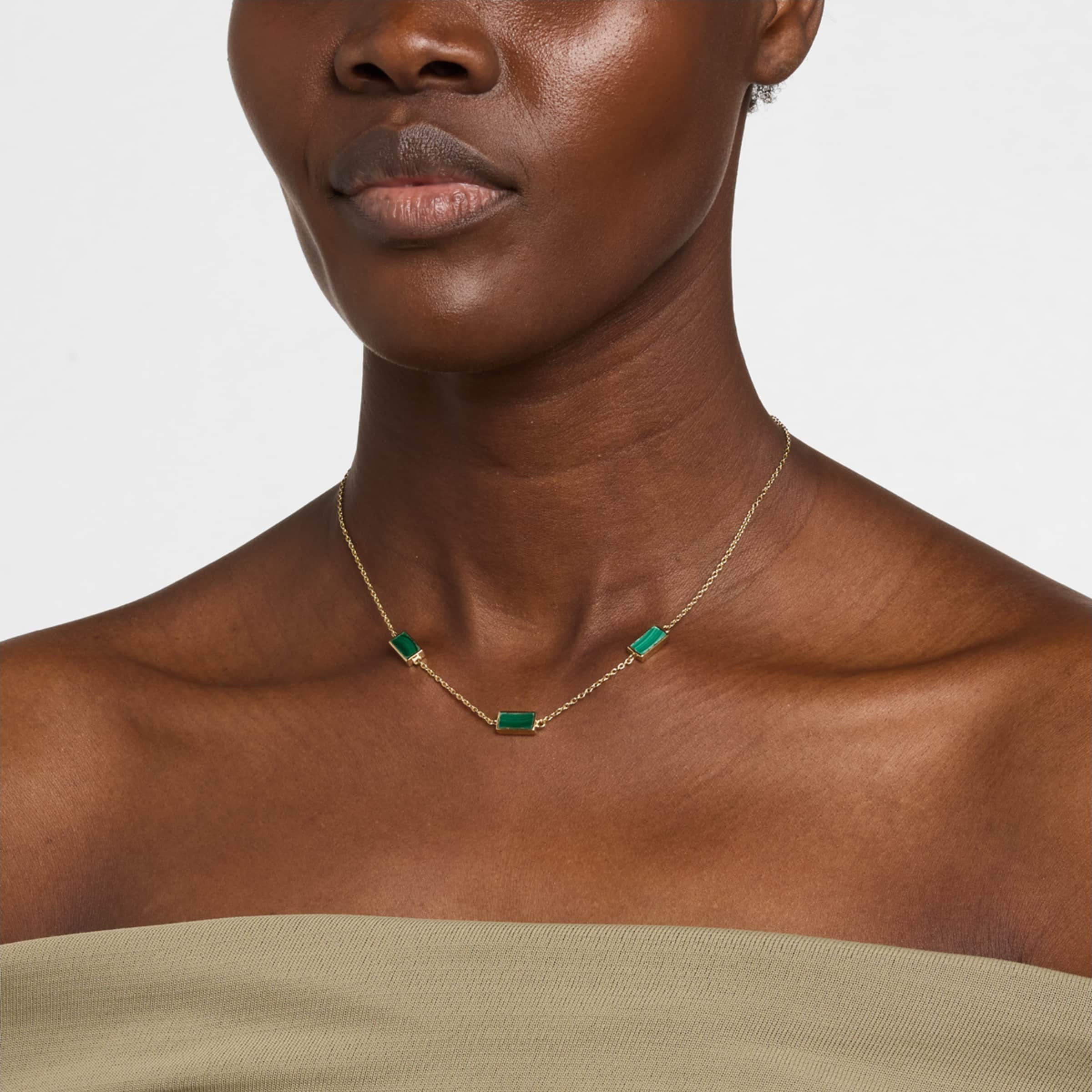Woman wearing gold vermeil sterling silver three-station malachite rectangle choker necklace at collarbone length over olive strapless top, showing banded green stone bezel settings, Jan Leslie luxury women's fine jewelry lifestyle.