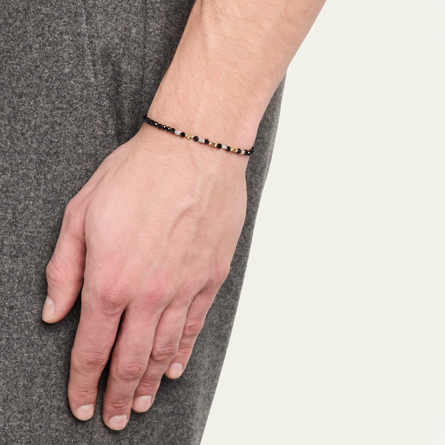 Man wearing black onyx beaded bracelet with gold and diamond accents on wrist.