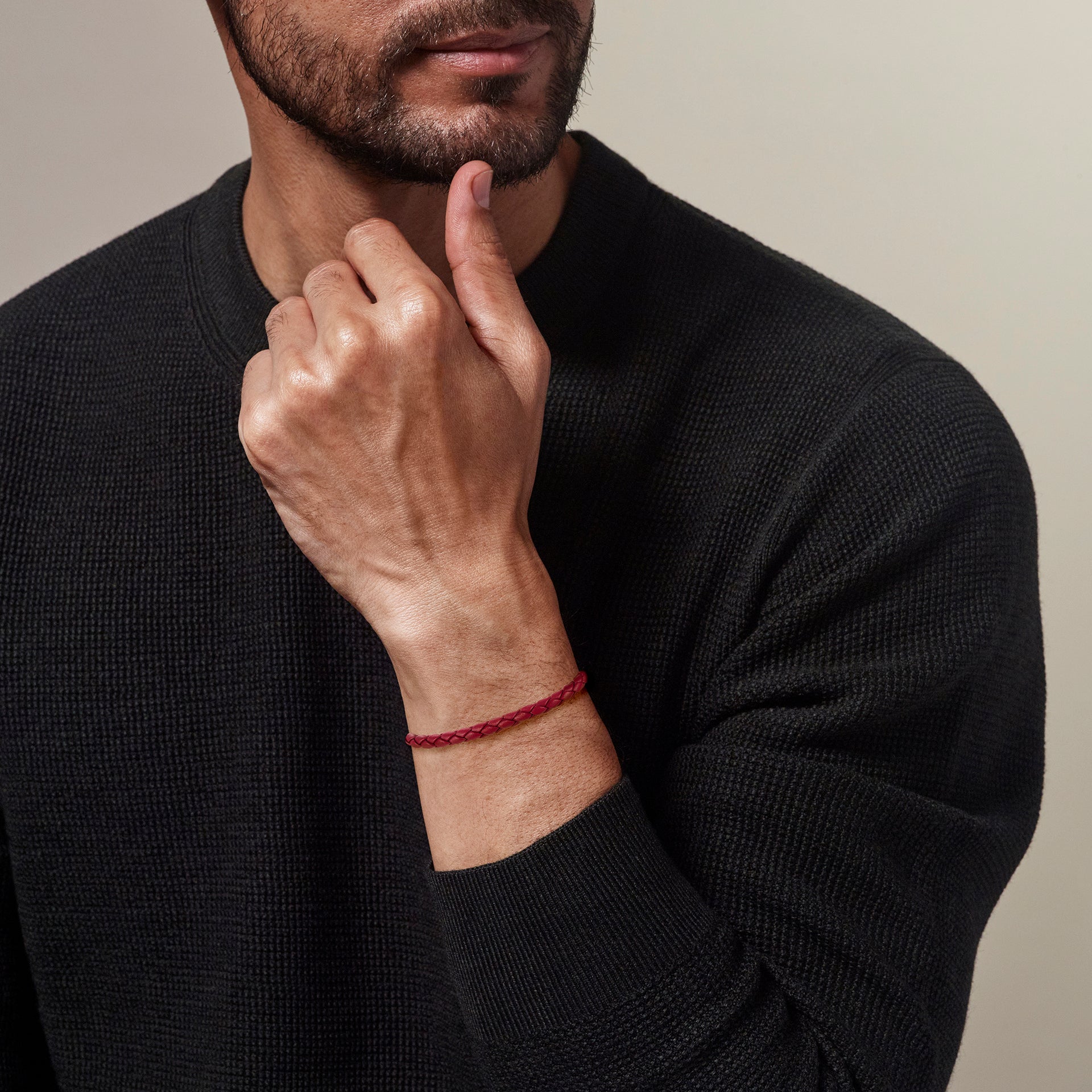 Red braided leather bracelet with magnetic clasp worn on man's wrist with black sweater