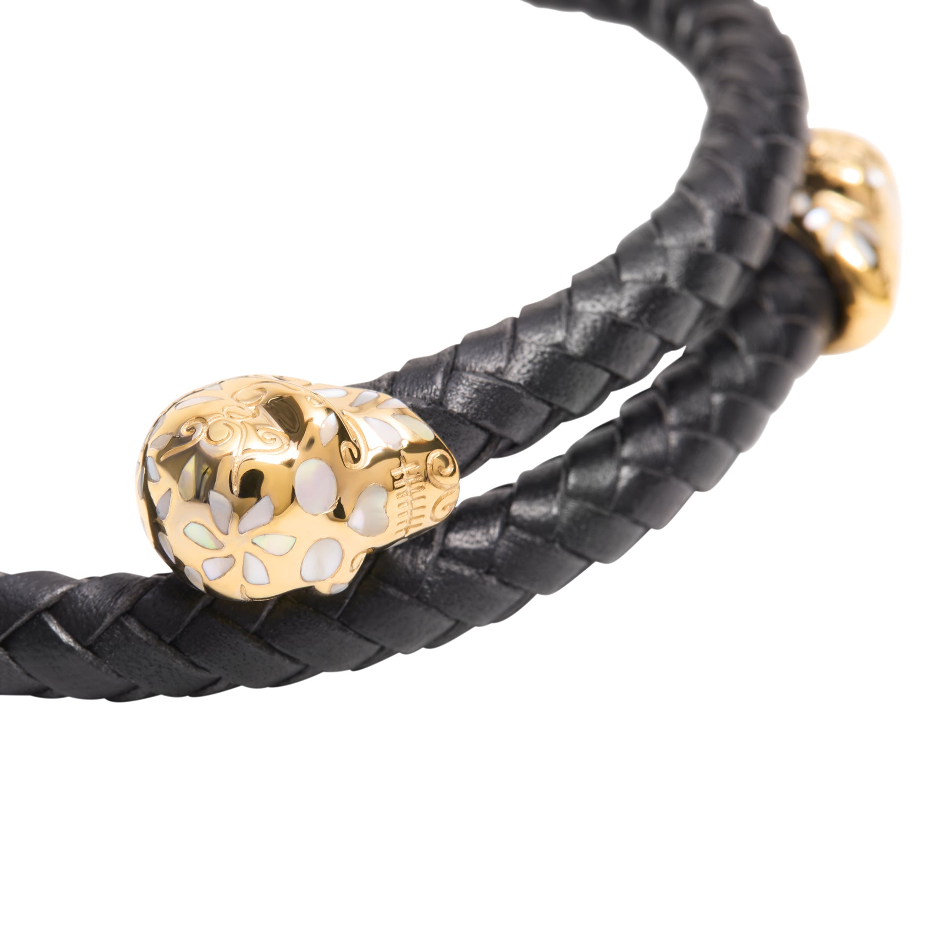 Close-up of the sterling silver sugar skull end caps on the brown braided leather bracelet  intricately engraved with floral scrollwork and mother-of-pearl inlay.