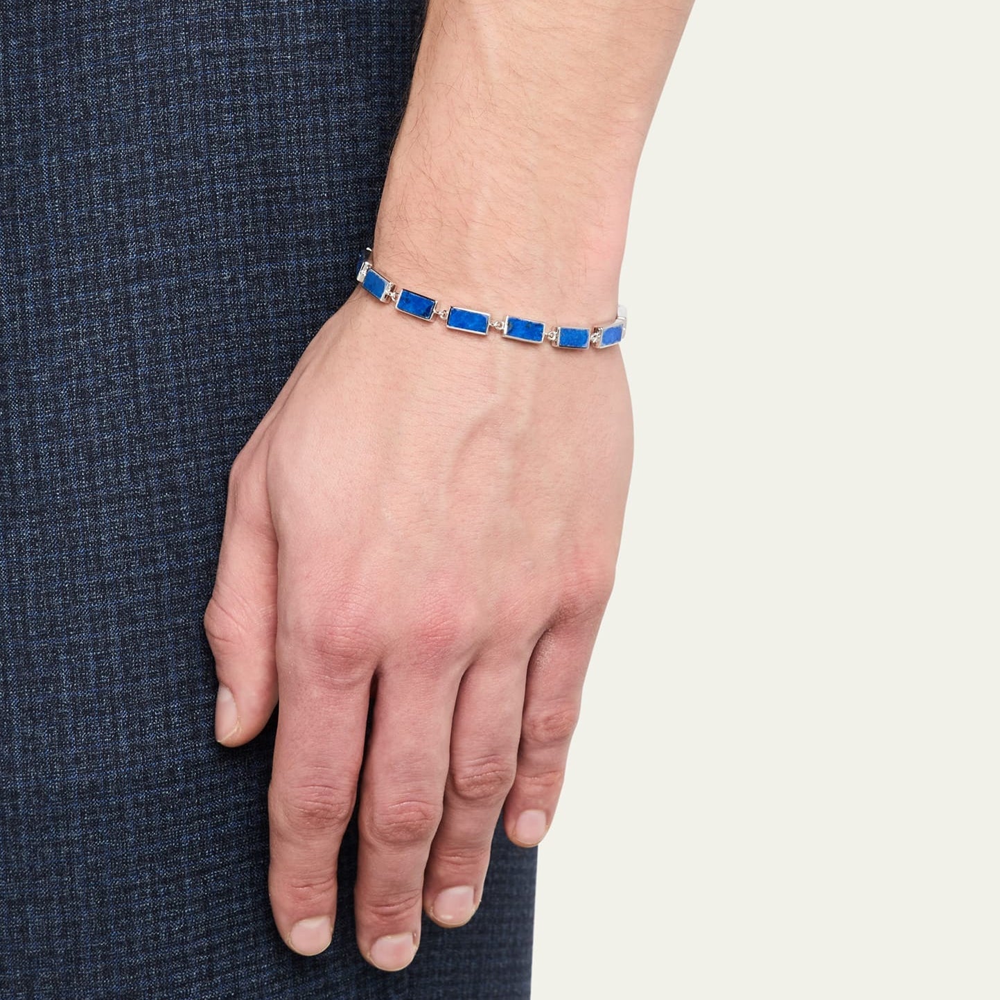 Man in dark denim jacket wearing sterling silver lapis lazuli rectangular station tennis bracelet at wrist showing continuous deep royal blue lapis stone face by Jan Leslie