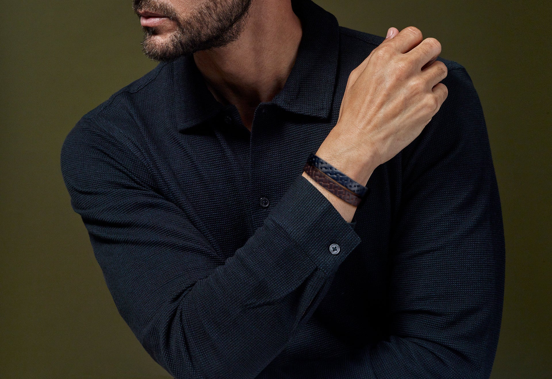 Man in navy shirt stacking navy and brown wide braided leather bracelets with silver clasp — Jan Leslie