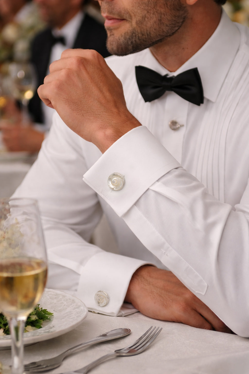 Round mother of pearl cufflink with polished sterling silver spiral rose detail worn on white French double cuff 