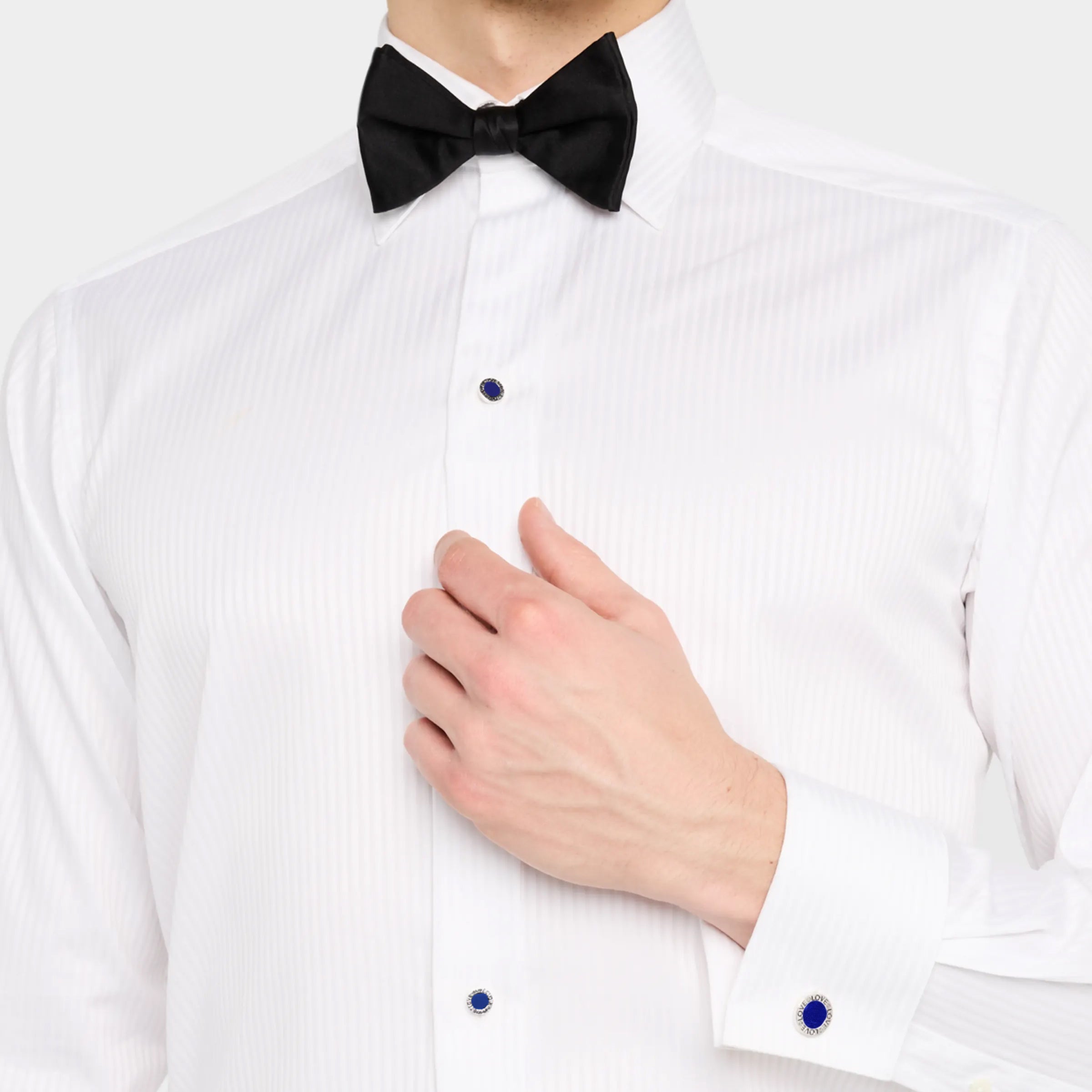 Man in white tuxedo shirt and black bow tie wearing blue lapis lazuli round cufflinks and matching shirt studs set, luxury black tie men's jewelry styling.