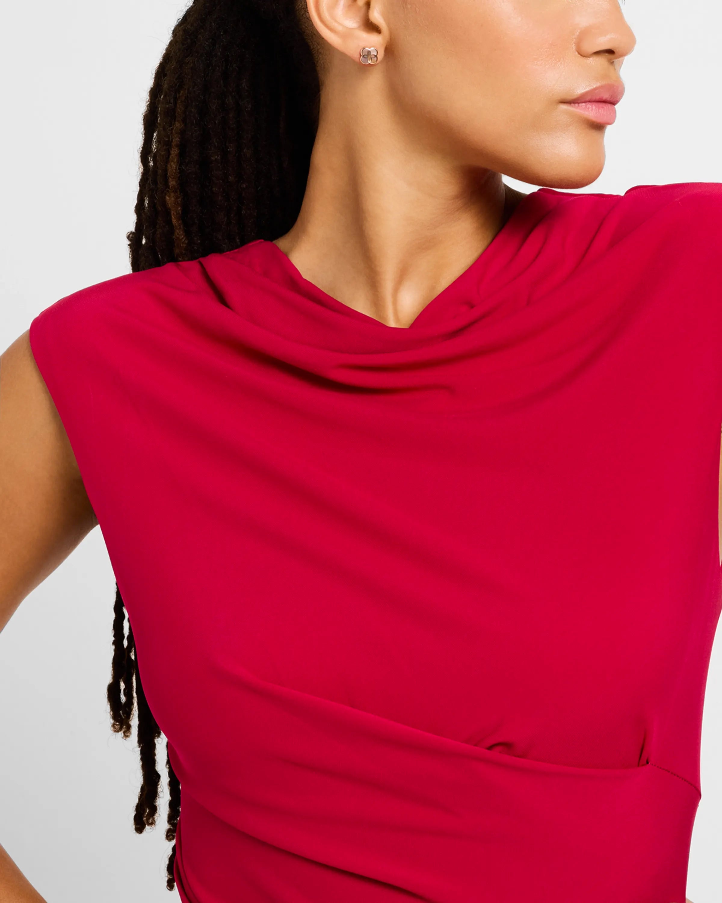 Woman in deep crimson dress wearing 18K gold vermeil sculptural petal clover stud earring at lobe showing four raised convex domed polished gold lobes by Jan Leslie