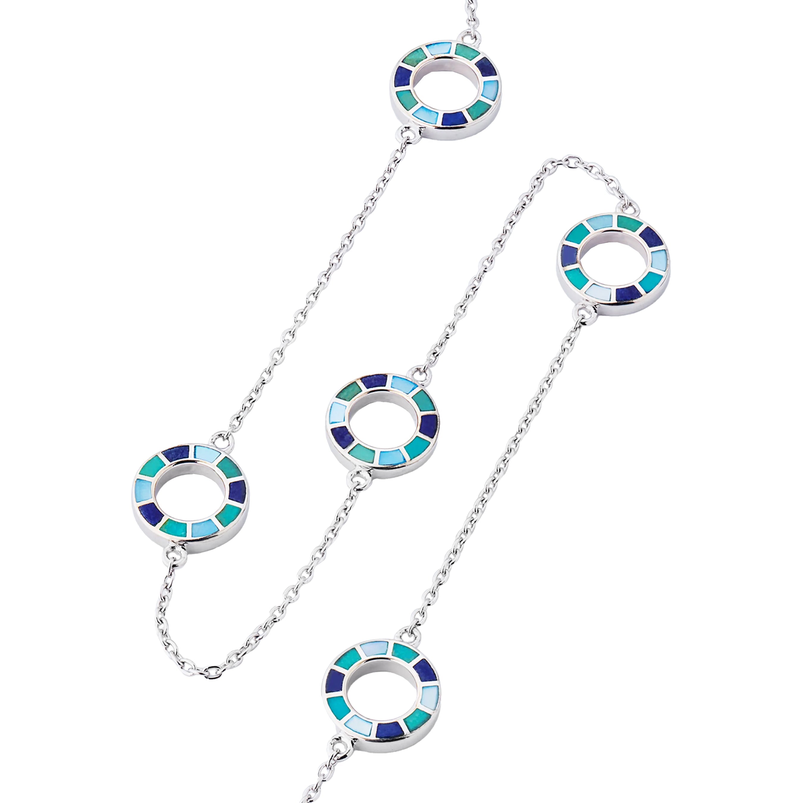 Close-up of five open circle pendants with segmented navy, teal, and sky blue enamel mosaic detail on sterling silver cable chain.