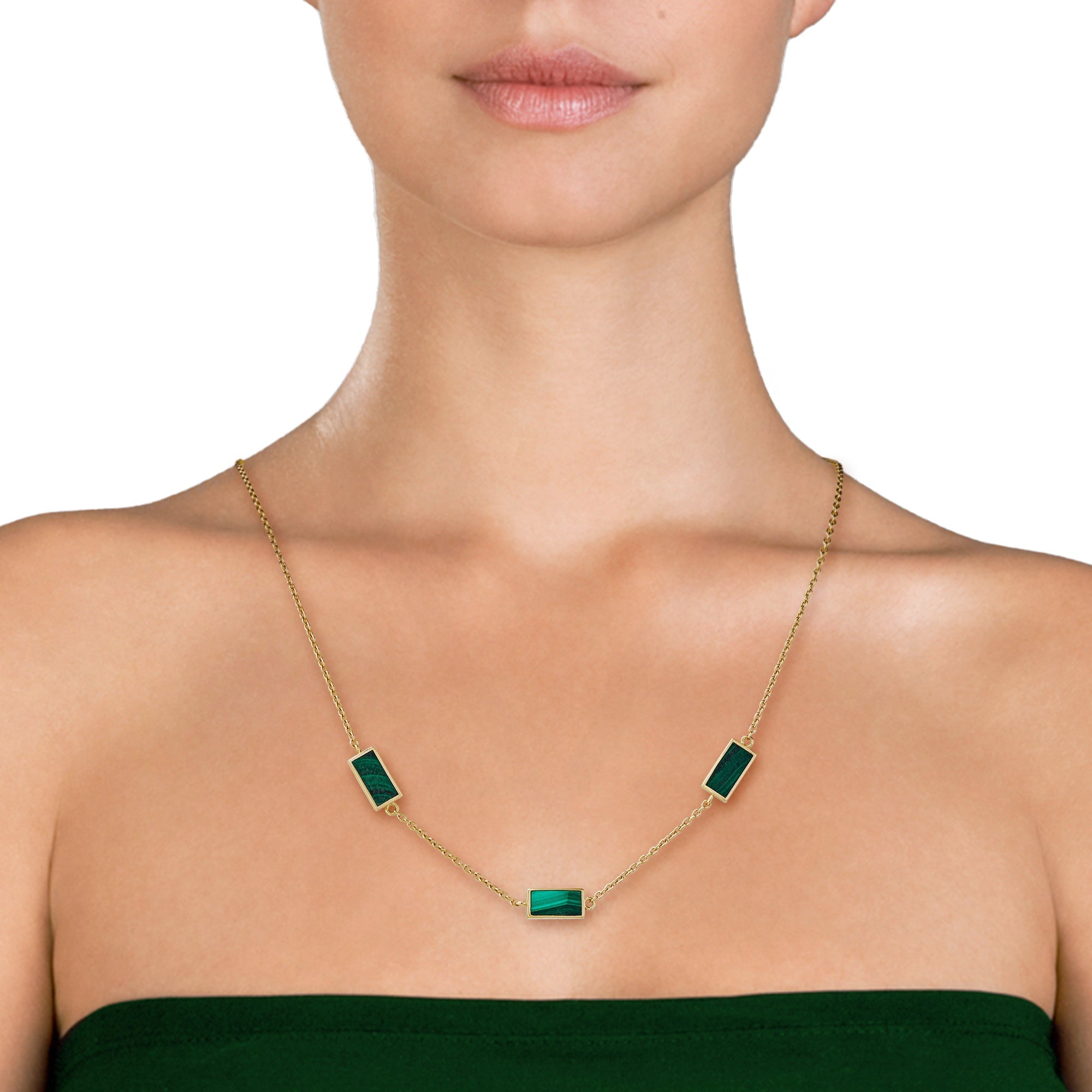 Woman in emerald green strapless dress wearing a gold cable chain station necklace with three rectangular malachite stone pendants in gold bezel settings.