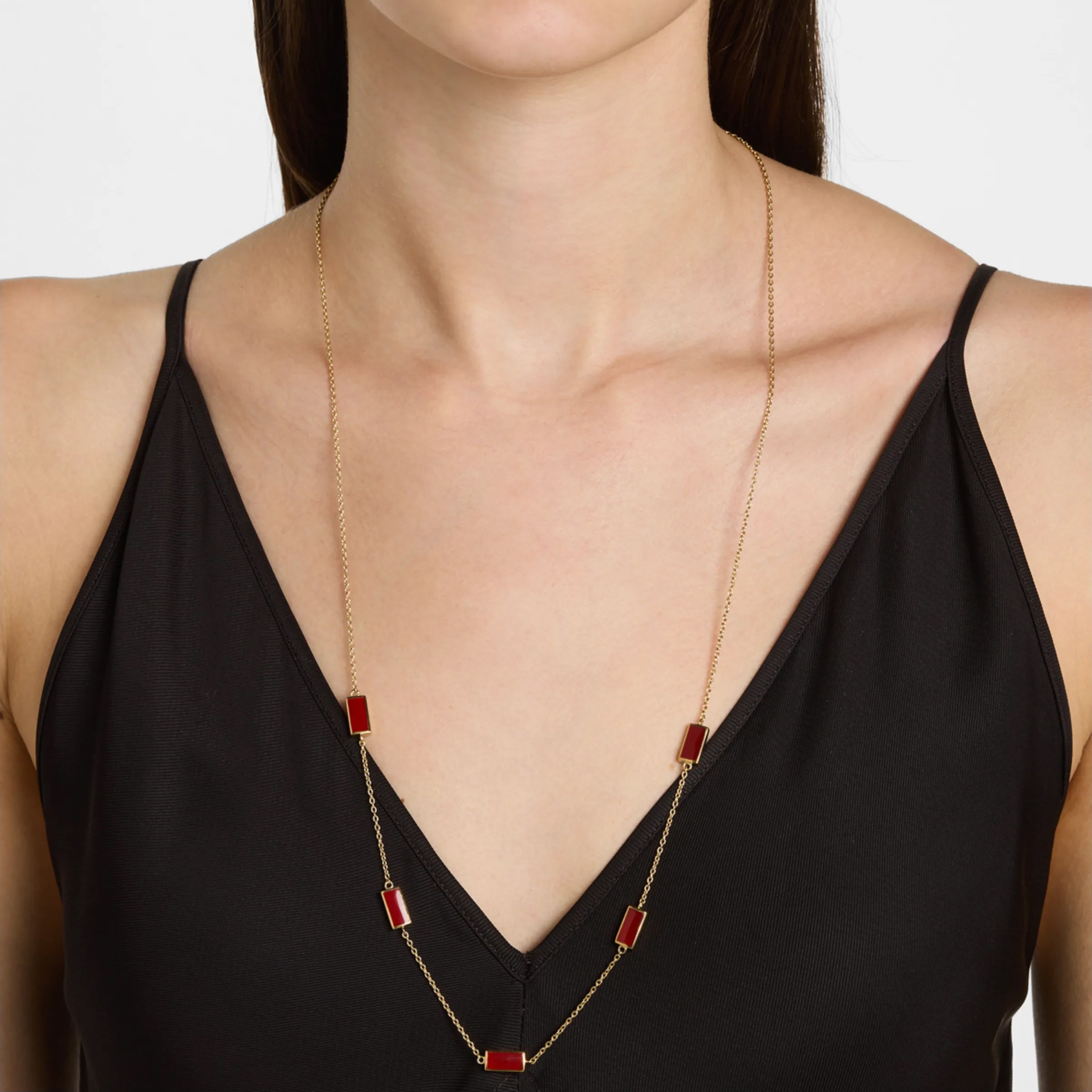 Woman wearing gold vermeil sterling silver five-station red carnelian rectangle long station necklace at chest length over black V-neck camisole, Jan Leslie luxury women's fine jewelry lifestyle.