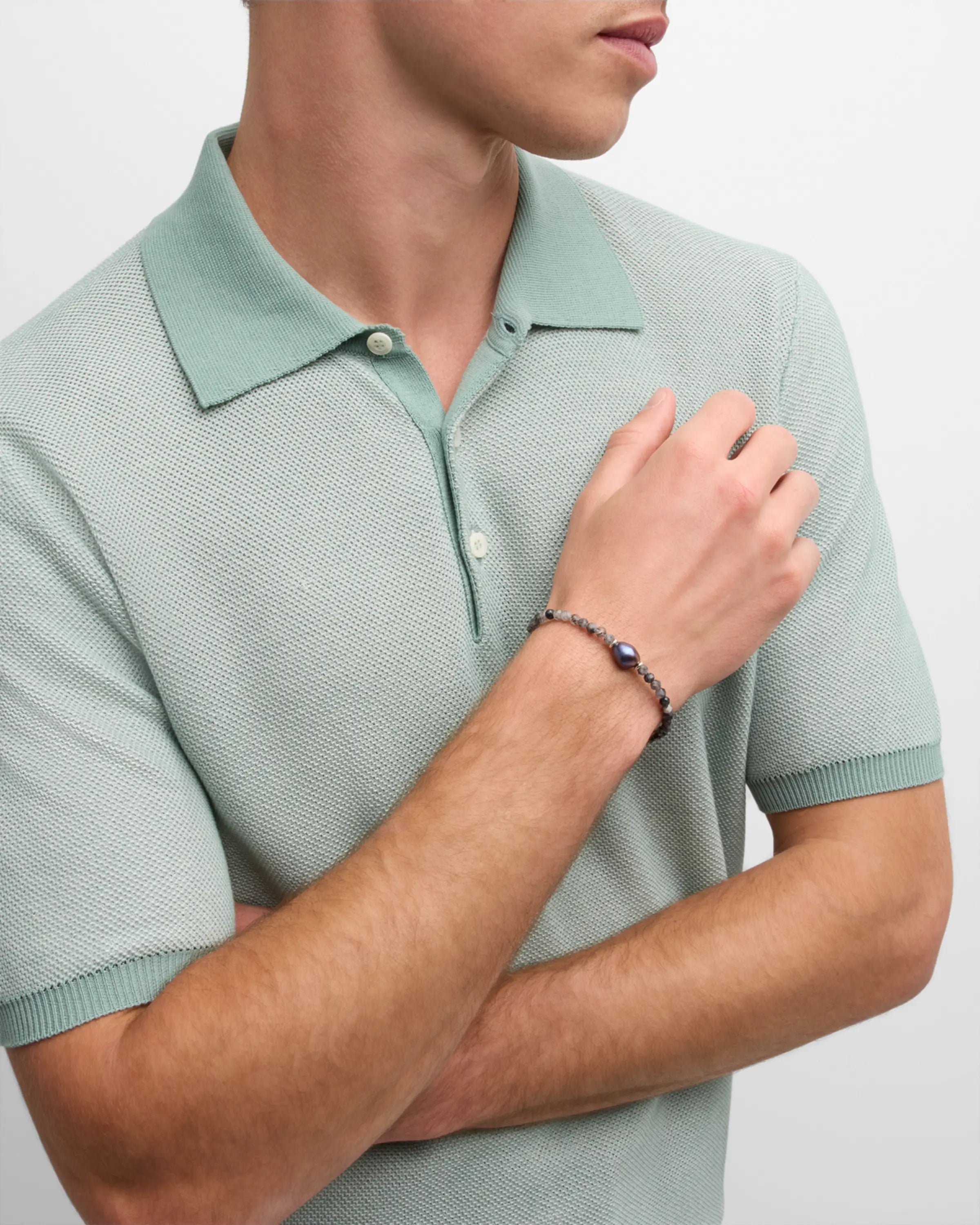  Man wearing black tourmalinated quartz and baroque peacock pearl bracelet on wrist with sage green polo shirt by Jan Leslie.