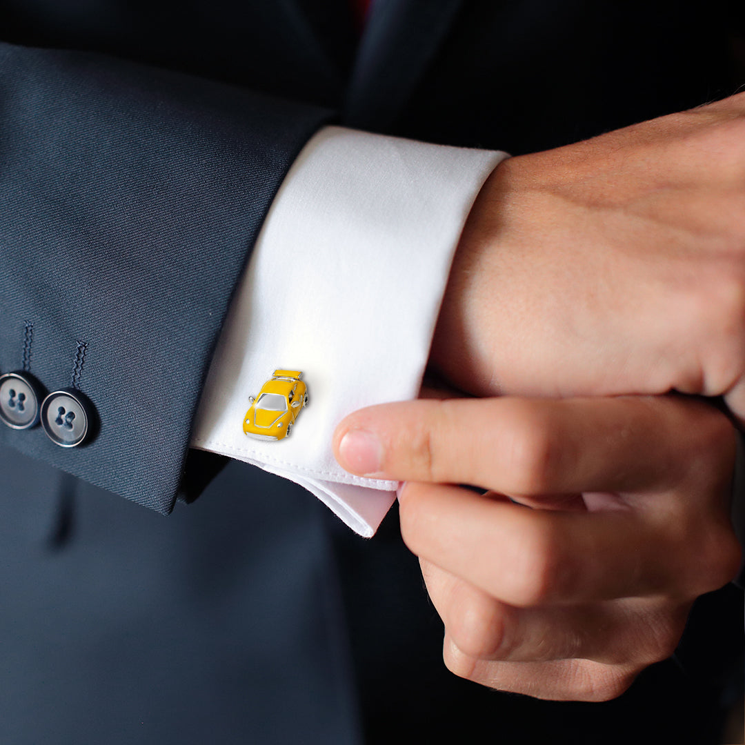 Man in navy suit adjusting white French-cuff shirt wearing yellow enamel sports car cufflink — Jan Leslie