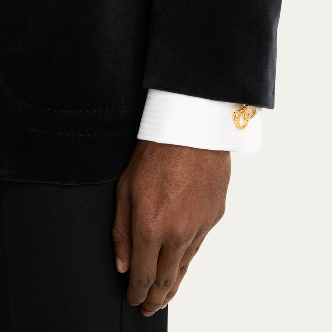 Man in black tuxedo wearing 18K gold vermeil sculptural handcuff cufflinks at white French cuff dress shirt showing gold handcuff motif with chain link and key charm by Jan Leslie