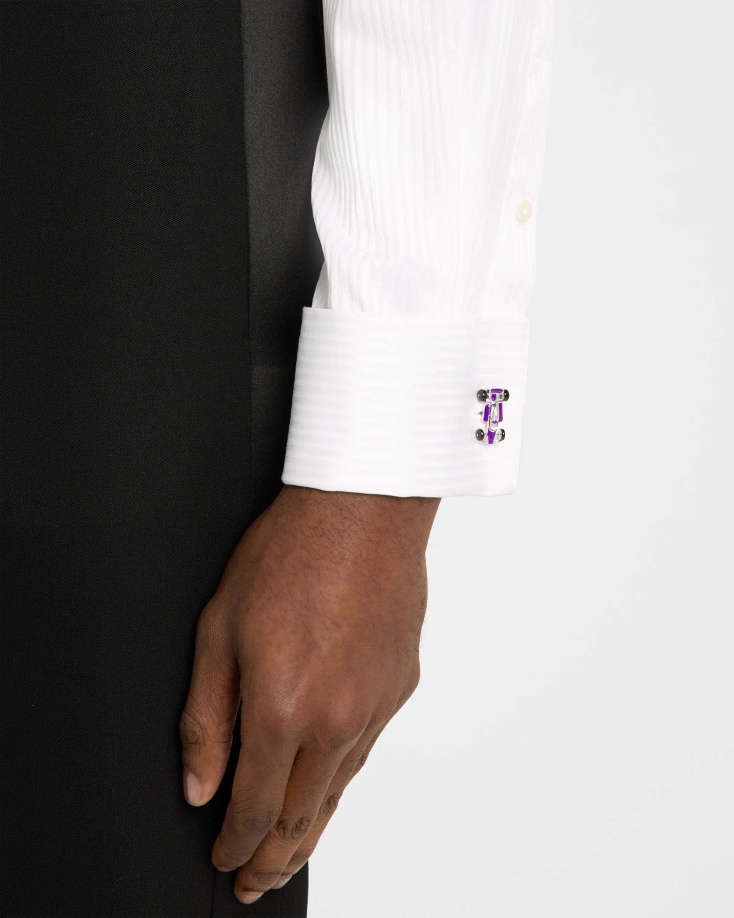 Man in black tuxedo jacket and white pleated bib dress shirt wearing sterling silver and purple enamel Formula 1 racing car cufflink on cuff, Jan Leslie 