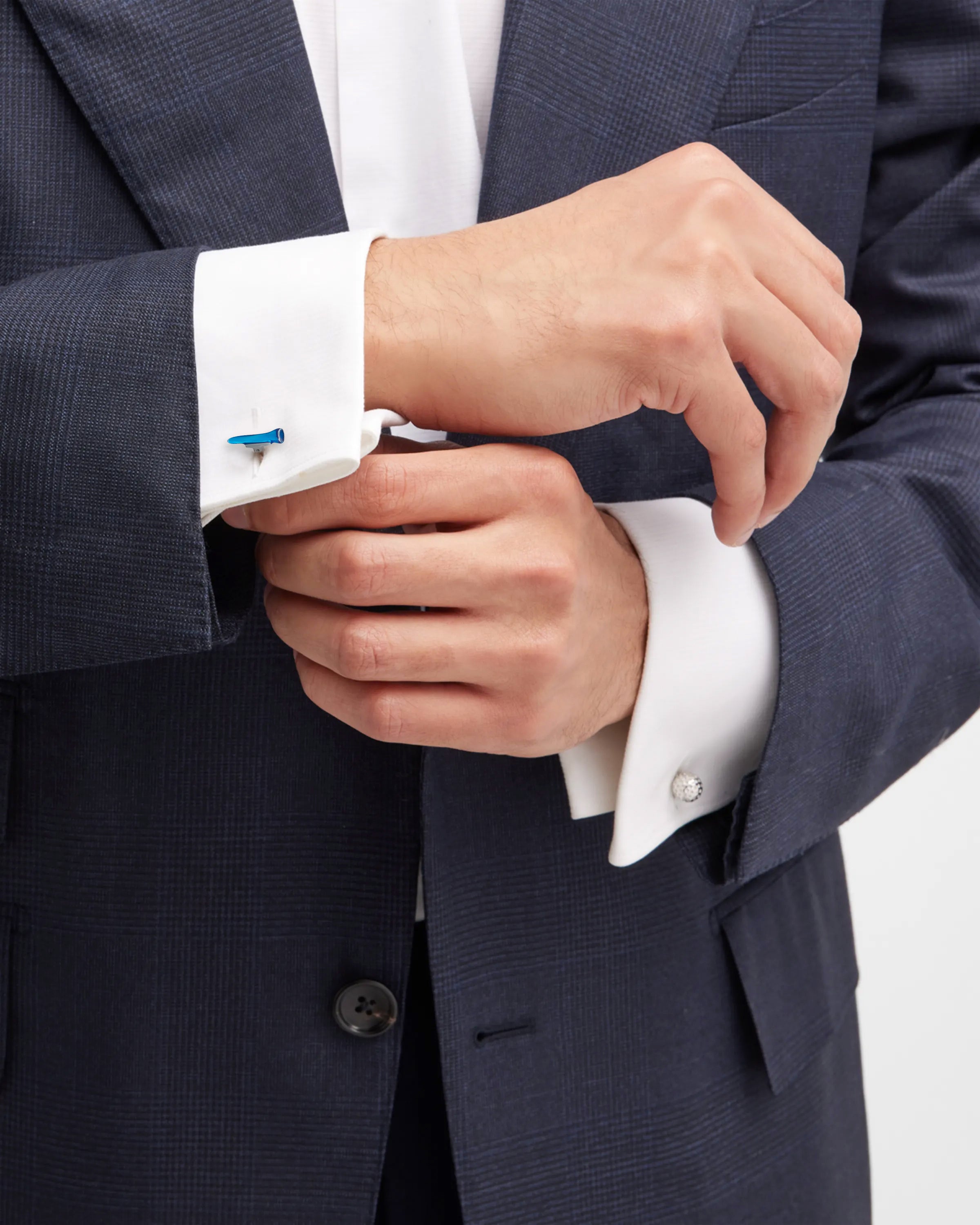 Close-up of man in navy suit adjusting white dress shirt cuff wearing sterling silver and blue enamel golf tee cufflink, Jan Leslie