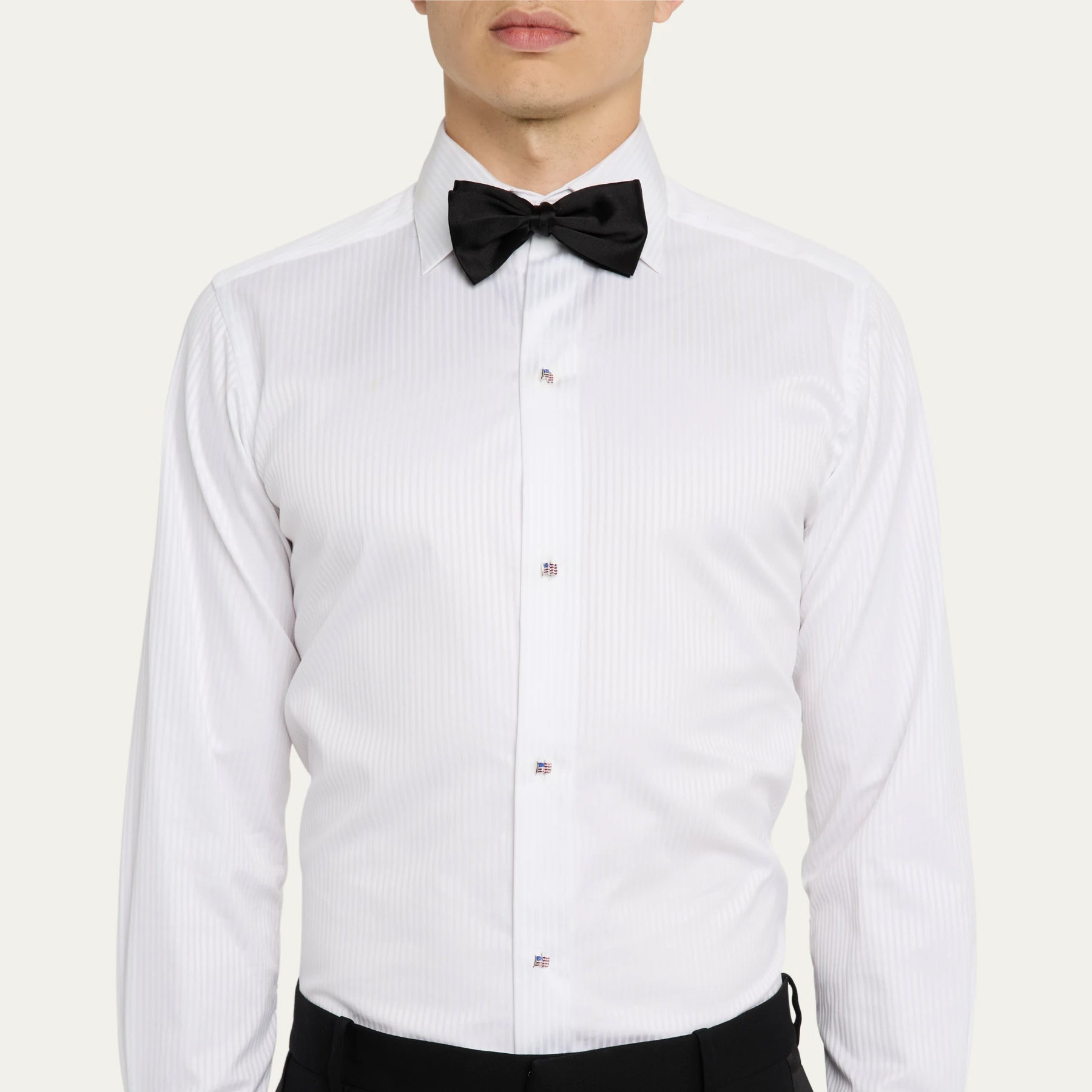 Man in white pleated tuxedo shirt and black bow tie wearing American flag enamel tuxedo studs down the placket.